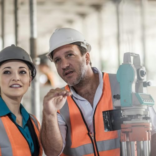 Surveyor explaining to female builder on construction site